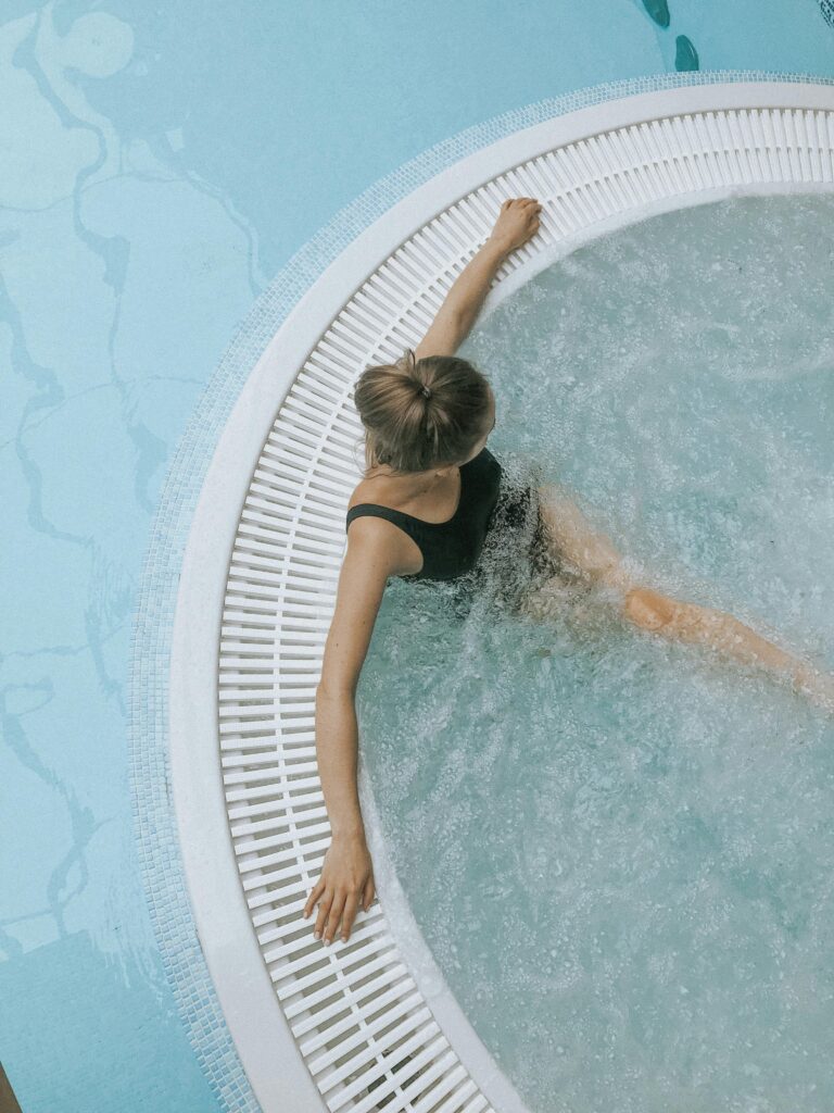 A person enjoys a serene soak in a stylish circular jacuzzi spa, ideal for relaxation.