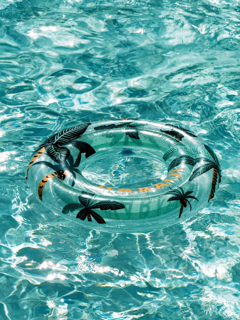Bright summer day with a tropical inflatable ring floating on clear pool water.