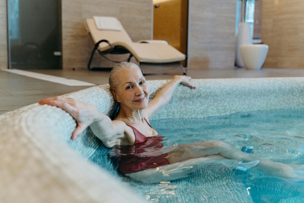 Elderly woman enjoying leisure time in an indoor pool, promoting healthy lifestyle and relaxation.